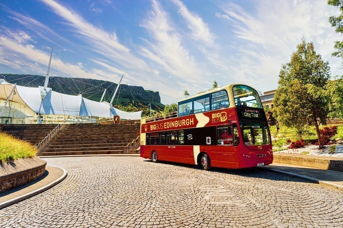 An open top double decker sightseeing bus on a street in Edinburgh. 