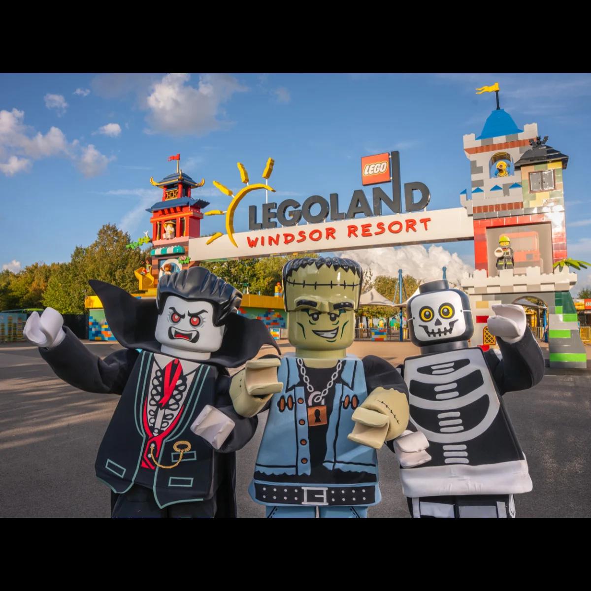 Three LEGO Halloween characters — a vampire, Frankenstein's monster, and skeleton — posing at the Legoland Windsor Resort entrance.