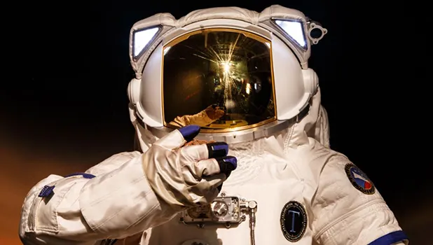 A figure in a white spacesuit with a reflective screen on the helmet