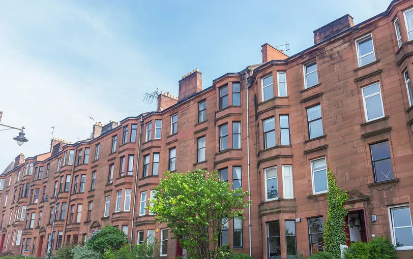 A row of brick tenement houses on a Glasgow street. 