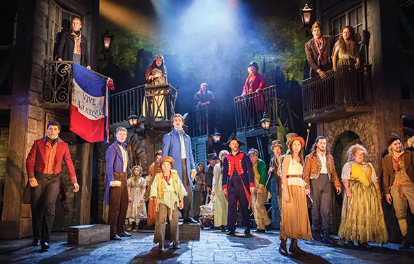 The cast of musical Les Miserables on stage, dressed in clothes from the French Revolution.