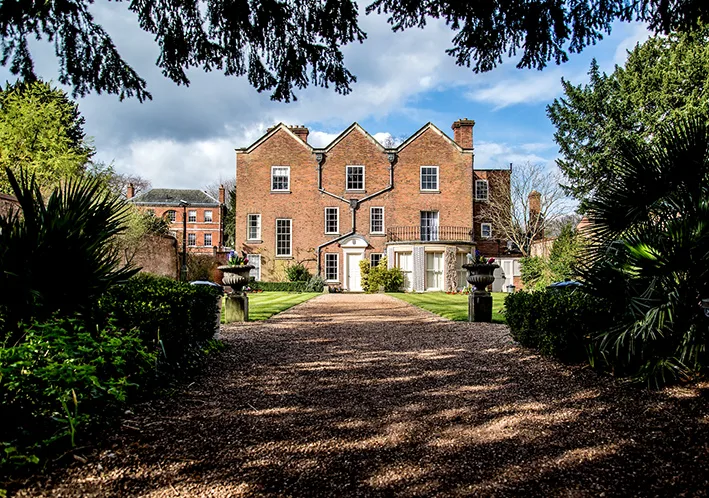 A gravel path leading to a brick stately home. 