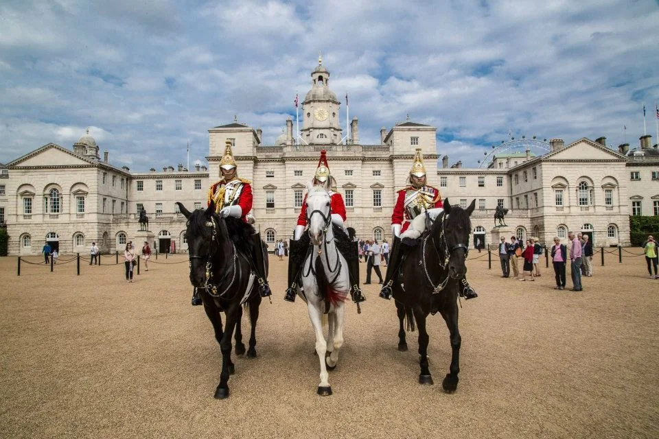 3 members of the Household Cavalry dressed in their military regalia and riding horses in front of Horseguards Parade.