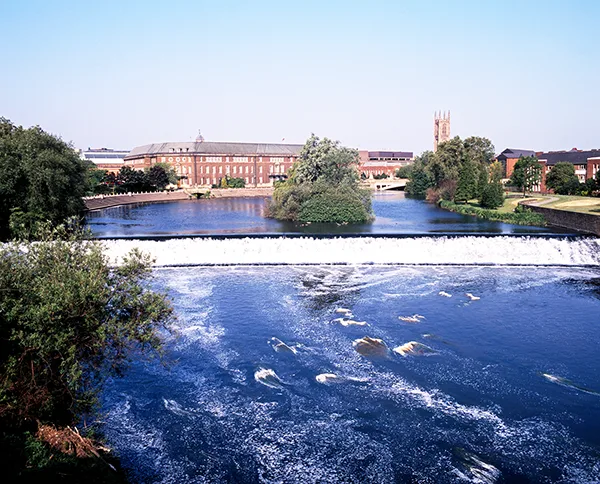 A wide river with red-brick buildings in the background.