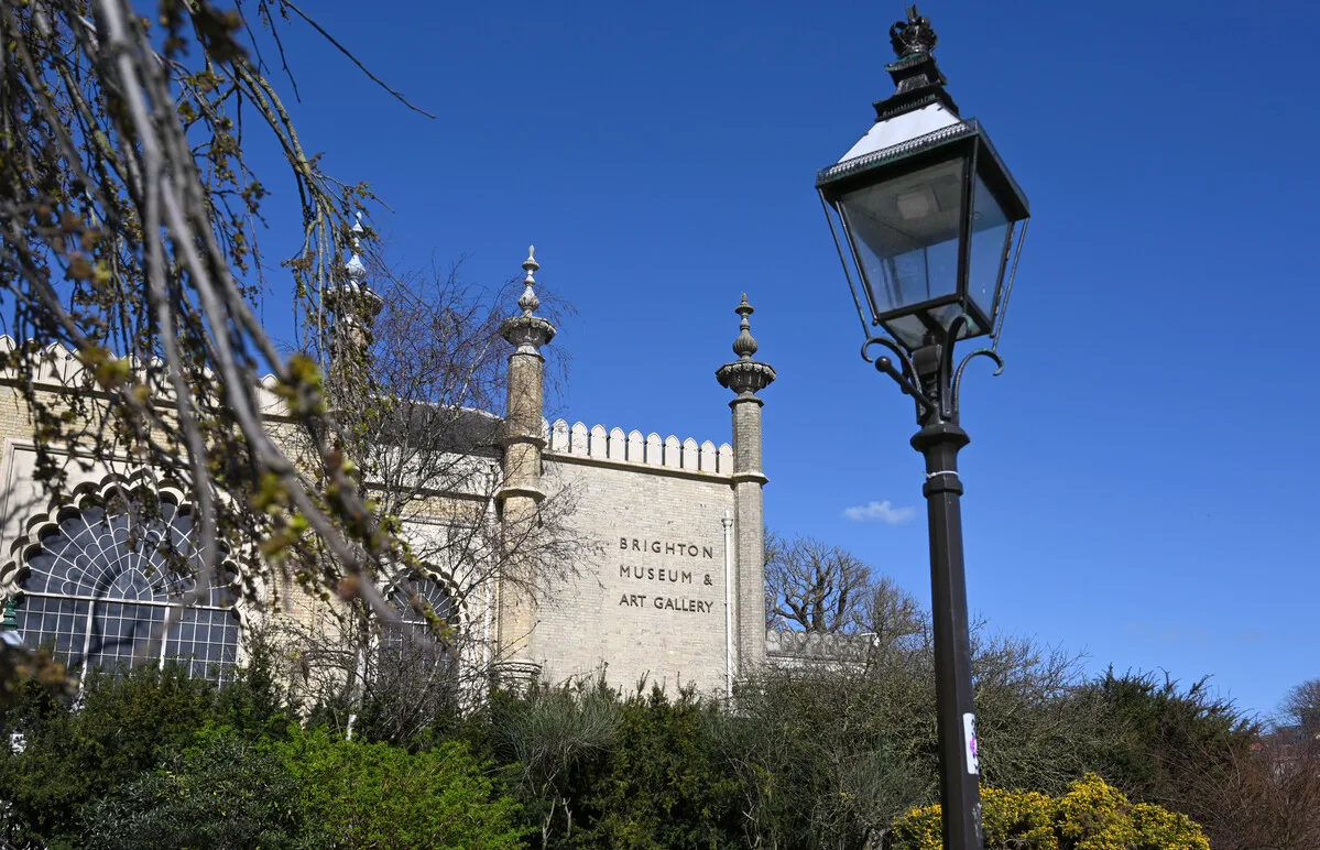 Castle-like entrance to Brighton Museum and Art Gallery sits underneath a blue sky with a black lamppost in the foreground.
