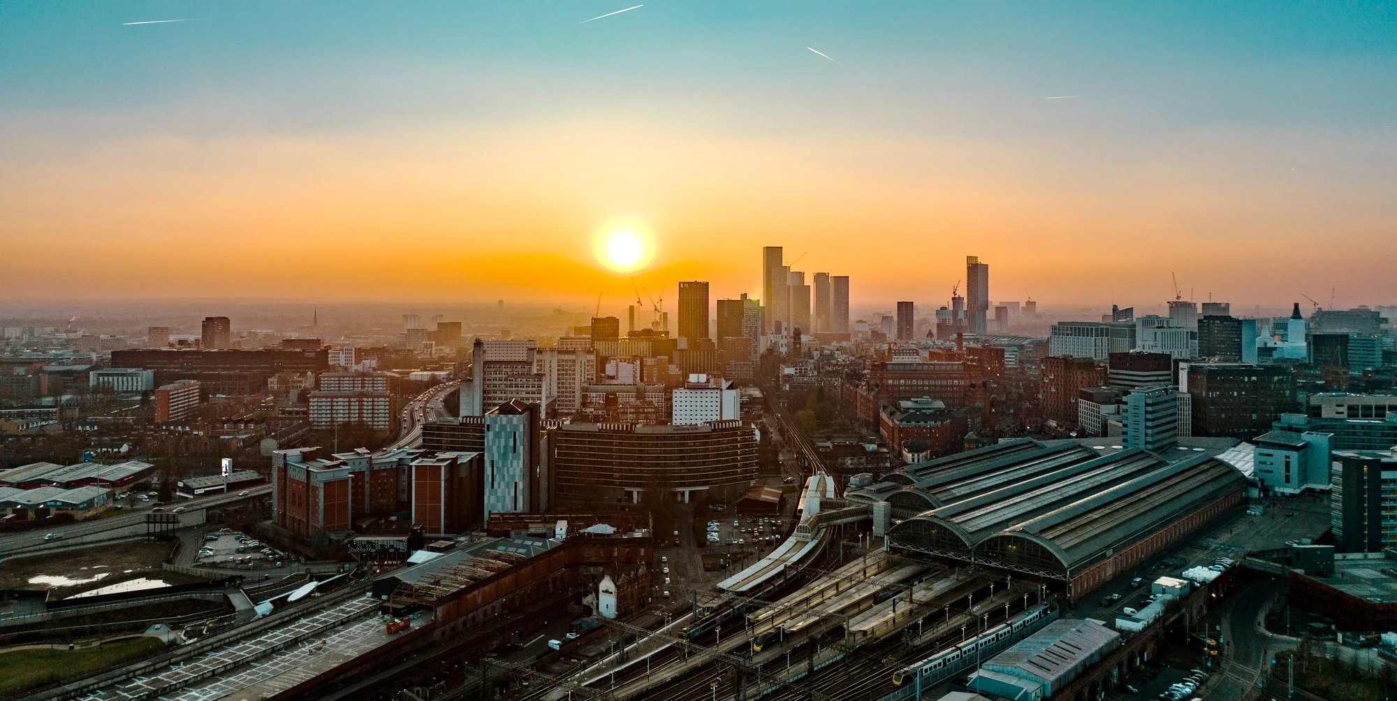 Aerial view of Manchester's Salford quays, with a large canal in the centre with bridges across, and tall buildings either side. 