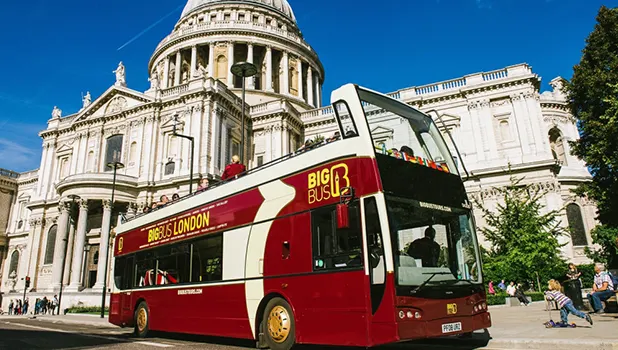 An open top sightseeing bus in front of St Pauls Cathedral