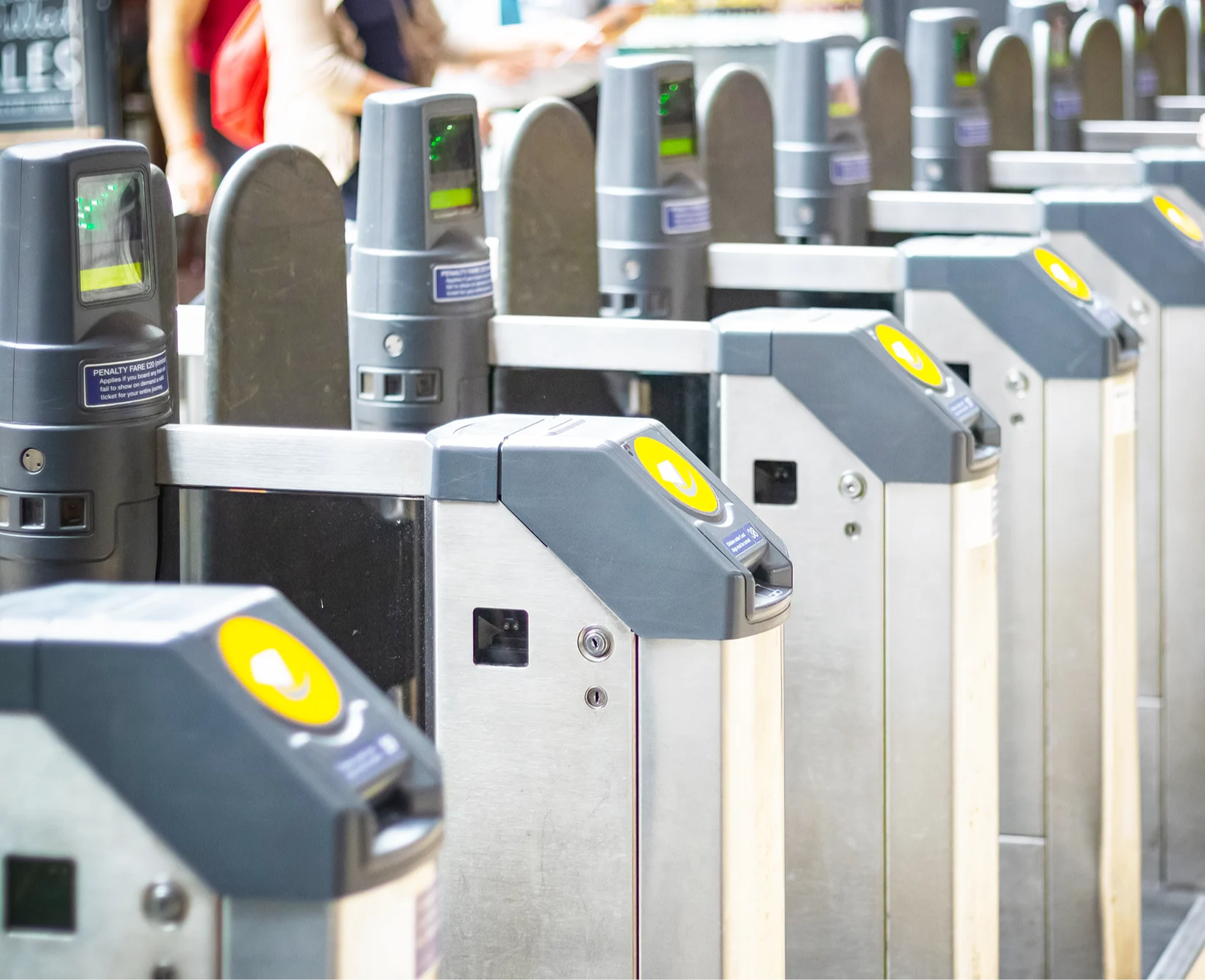 A row of ticket barriers with contactless readers at a train station