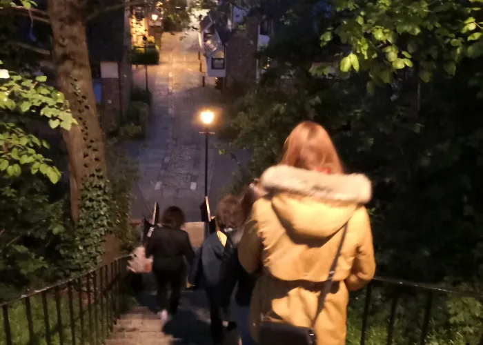 Women shown from behind, walking down a steep stone staircase at night. 