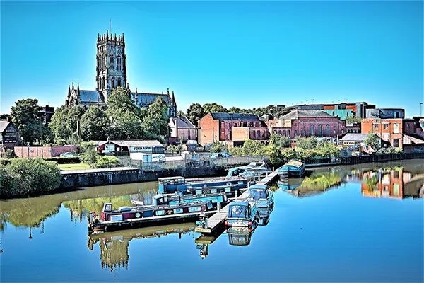 A large church overlooking lower redbrick buildings and a river. 