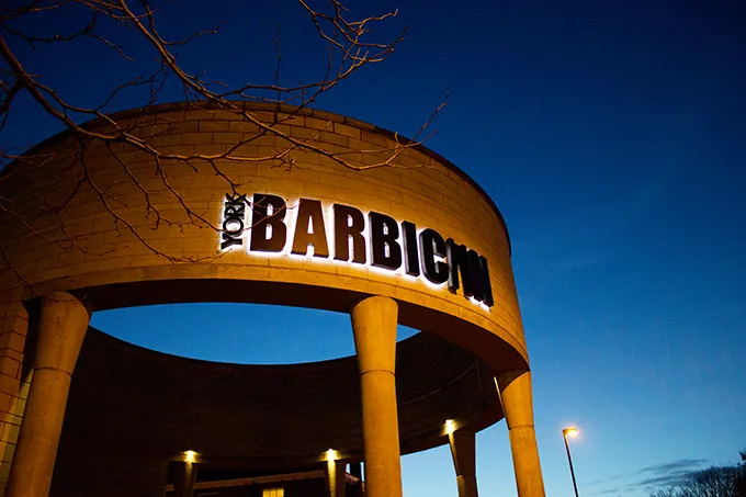 The stone pillars and sign of the entrance to York Barbican theatre at night. 