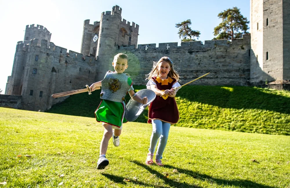 2 young white girls wearing knights fancy dress in front of Warwick Castle