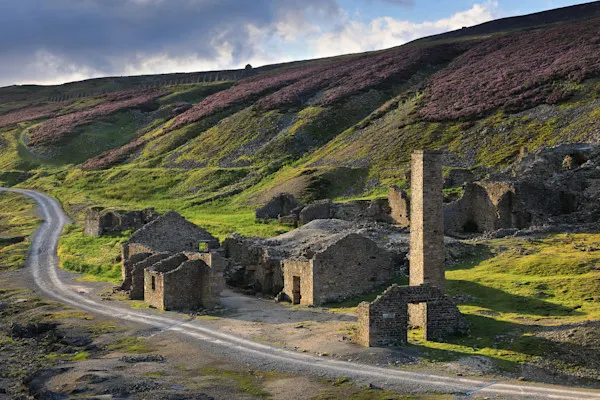Yorkshire National Park ruins of an old mining facility, with purple heather-covered hillsides rising in the background.