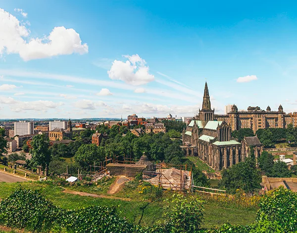 View from a cemetery on a hill overlooking a large cathedral and the city of Glasgow.