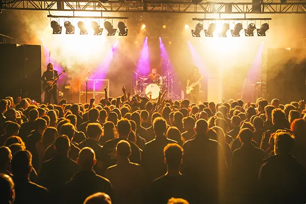 View of an audience seem from behind, watching a band playing onstage in a club