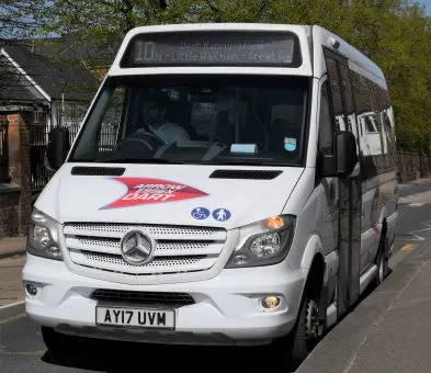 A white wheelchair accessible minibus parked at the side of a road
