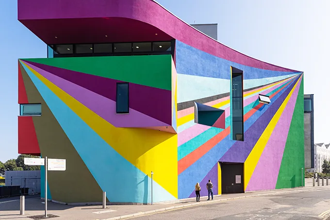 A modern building which is painted in stripes of different bright colours. 