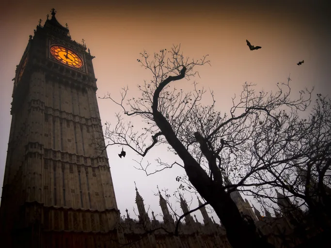 Big Ben at dusk with a shadowy tree and bats flying past