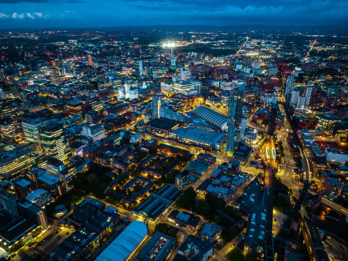 Aerial view of Manchester city scape with bright lights lighting up the streets and buildings.