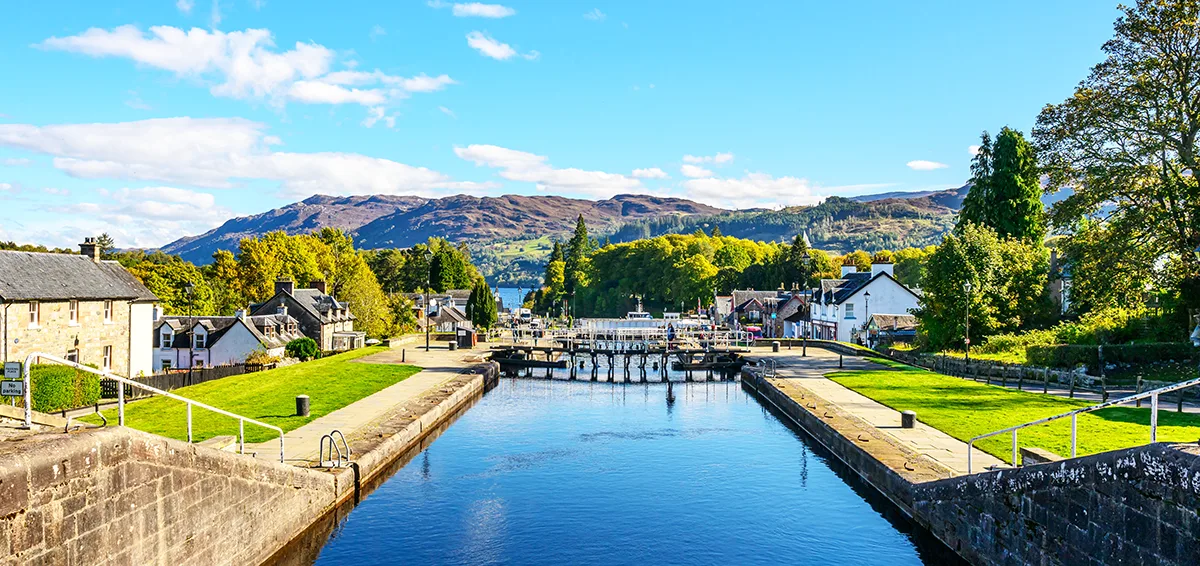 A peaceful rural canal with rolling hills in the distance.