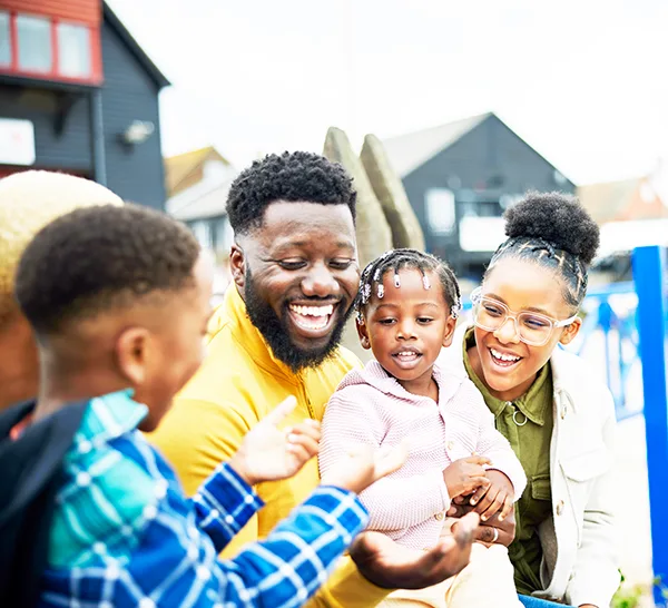 A Black family laughing at the seaside. 