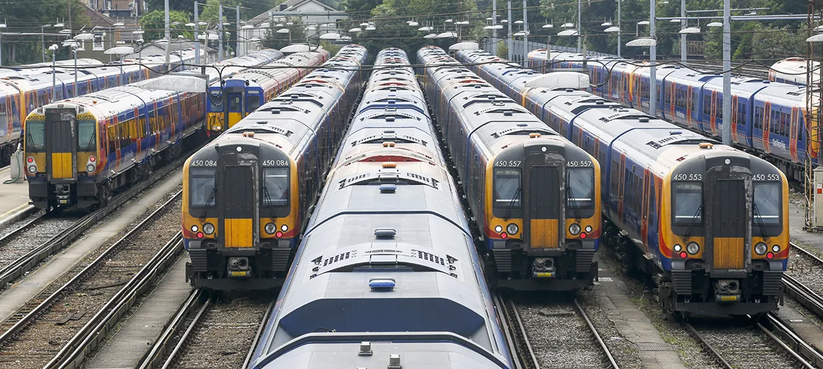 Multiple commuter trains with yellow and blue livery parked in a rail depot with parallel tracks.