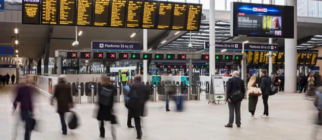 The concourse at London Bridge station with departure board at the top and blurry image of travellers waiting by the ticket gates.