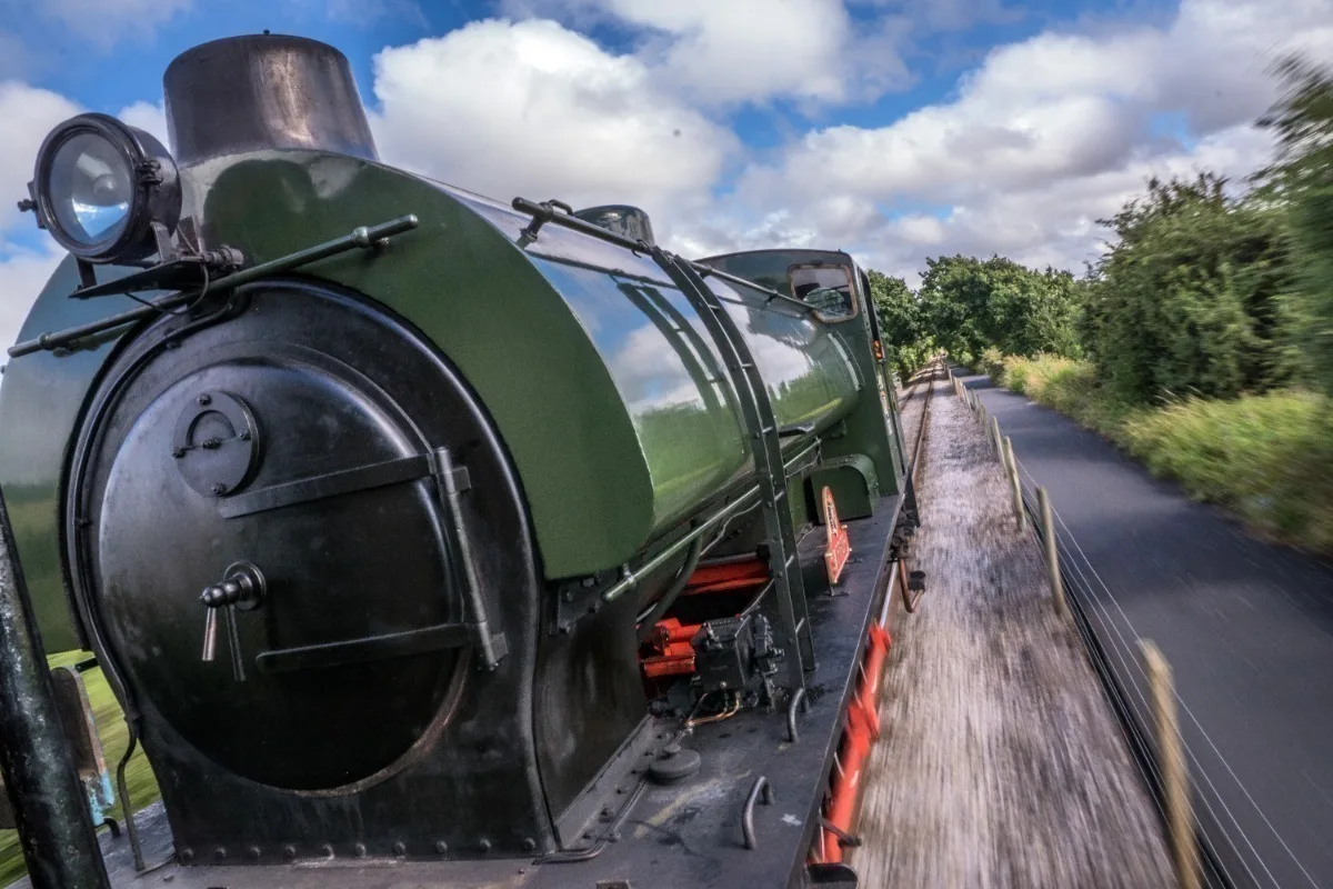 A dark green heritage steam train on a track. 