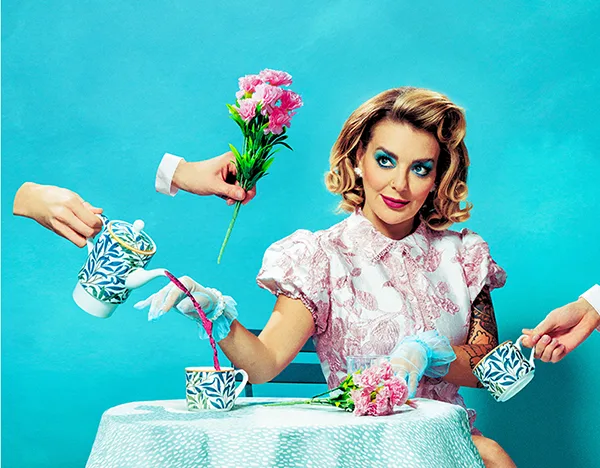 Stylised image of actor Sheridan Smith wearing a pink dress at tea party with floating hands offering flowers and pouring tea against a bright turquoise background