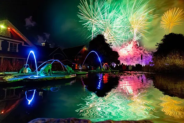 Fireworks exploding in the night sky and reflected in water.