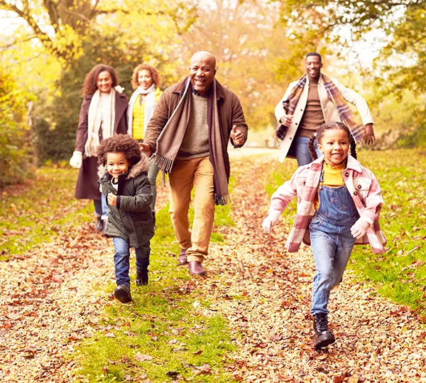 Smiling multigenerational Black family walking through autumn countryside. 