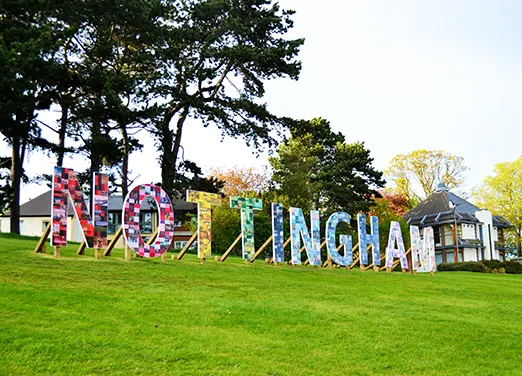 Large colourful wooden letters spelling NOTTINGHAM on a green lawn. 
