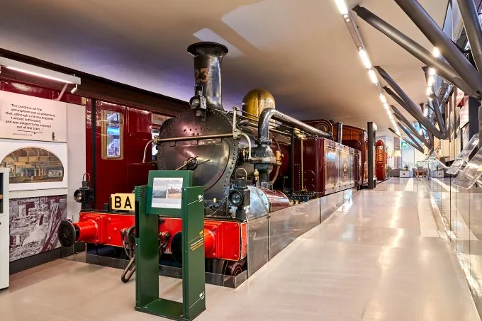 Metropolitan Railway A class steam locomotive No 23 on display at London Transport Museum being lit up by fluorescent lighting indoors.
