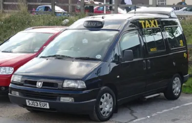 A black wheelchair accessible taxi parked in a car park