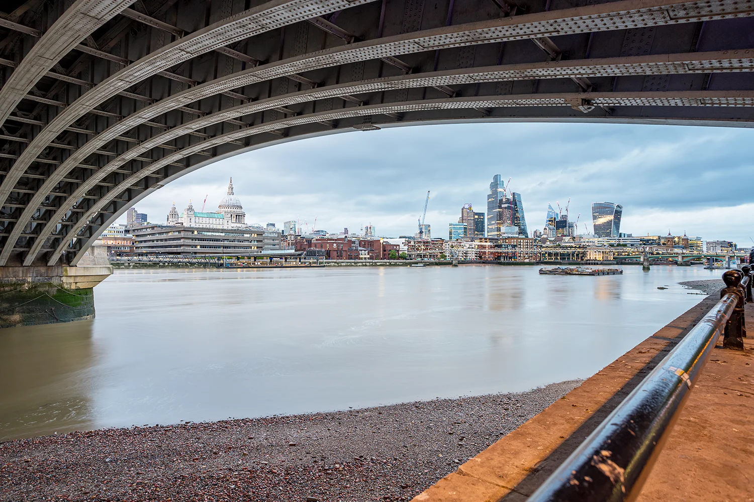 The view looking east down the Thames from under Blackfriars bridge, with St Paul's Cathedral and Canary Wharf visible in the background.