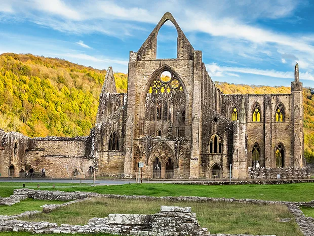 The ruins of Tintern Abbey, in front of green hillside. 