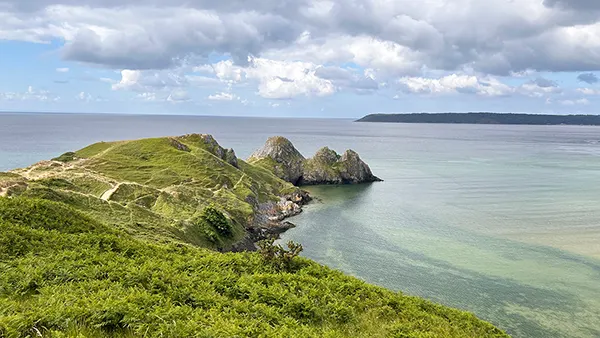 A rocky outcrop covered with plants, with a clear blue sea surrounding it. 