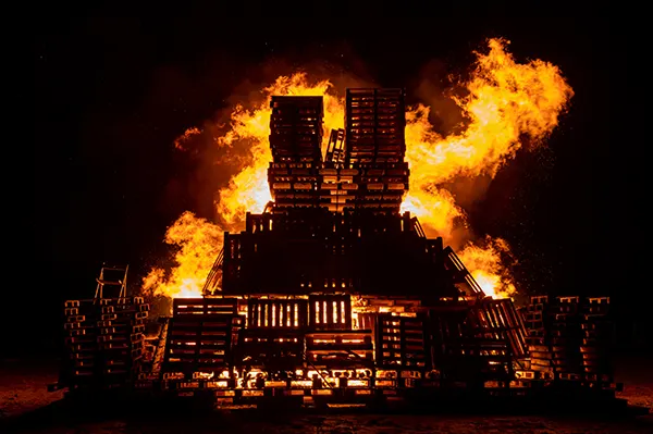 An enormous bonfire burning against a black night sky. 