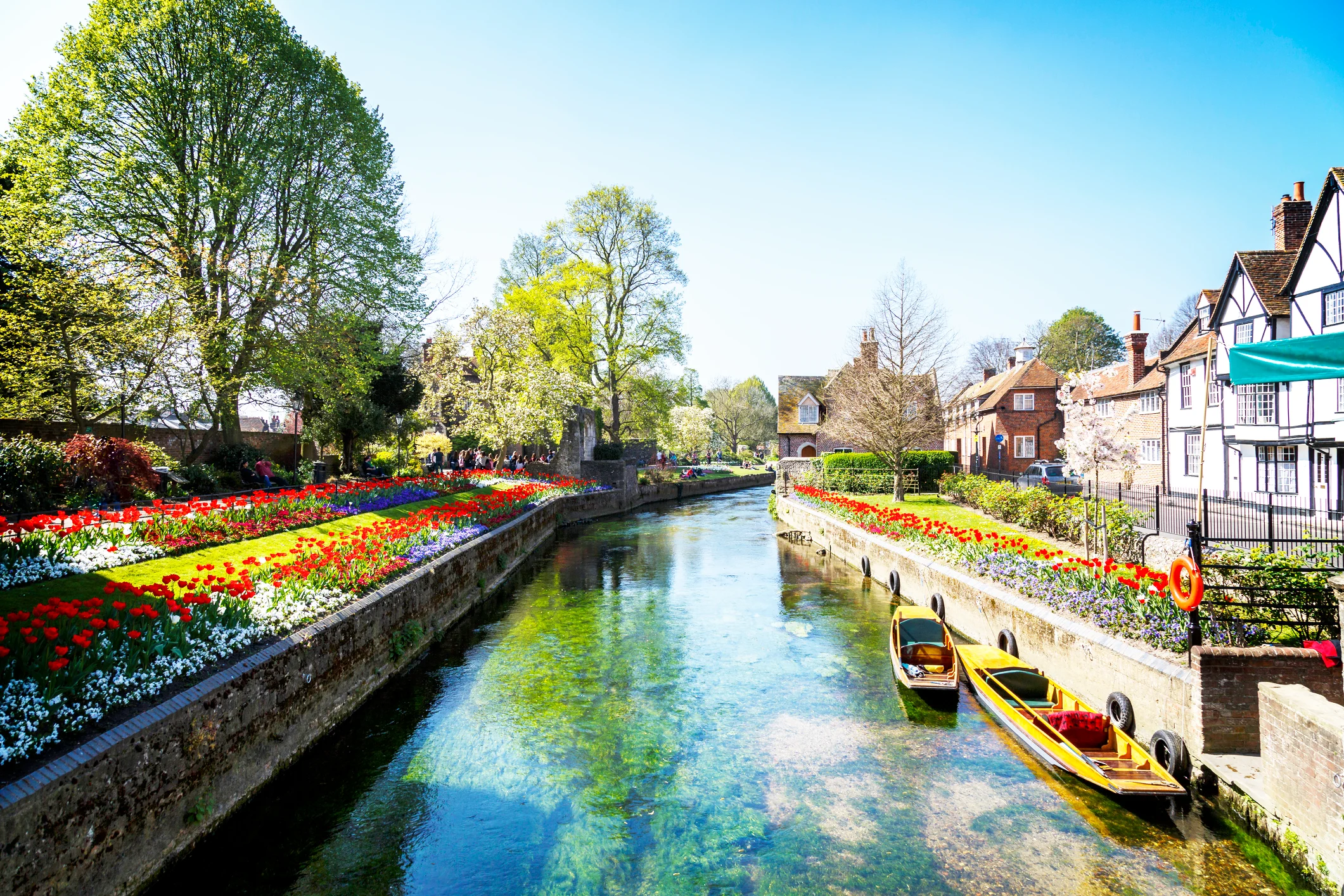 A river in an English village with colourful flowerbeds on each bank