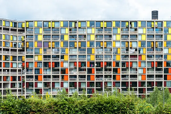 A large block of flats built of concrete with brightly coloured panels and large windows.