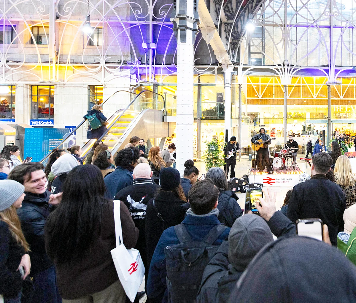 A band playing a concert at a station with an audience looking on. 