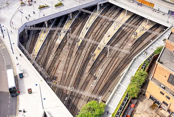 Aerial view of a train station with multiple railway tracks and platforms, and surrounding urban area.
