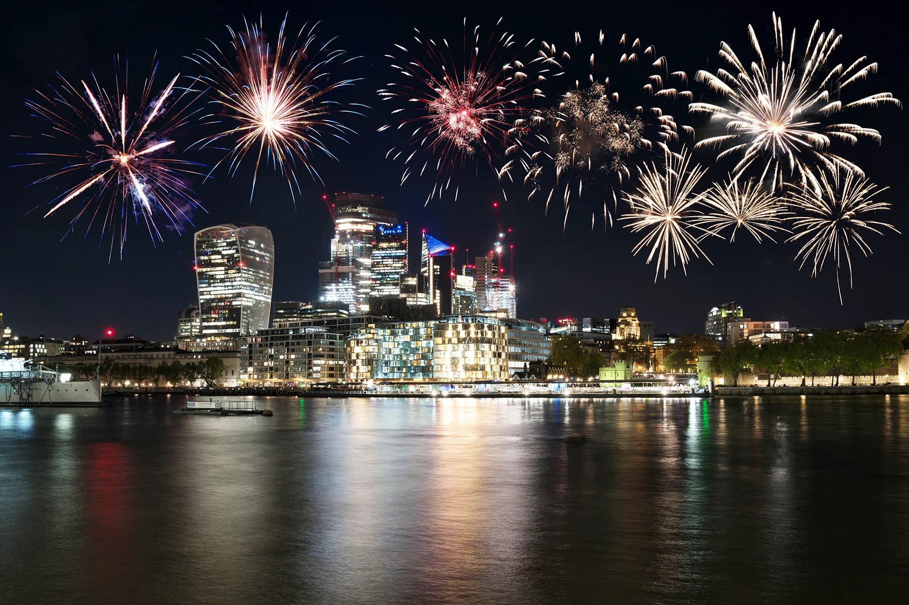Fireworks exploding in the night sky over the river Thames in central London. 