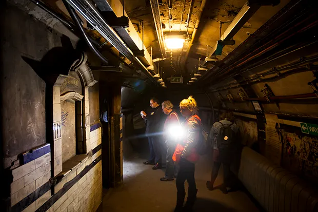 A group of people exploring a disused London Underground tunnel.