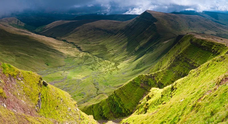 Steep green mountainside seen from above. 