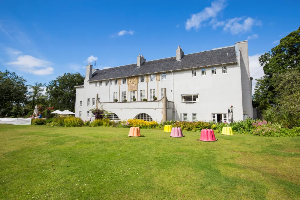 The outside of Charles Rennie Mackintosh's House for an Art Lover in Glasgow with a bright blue sky behind