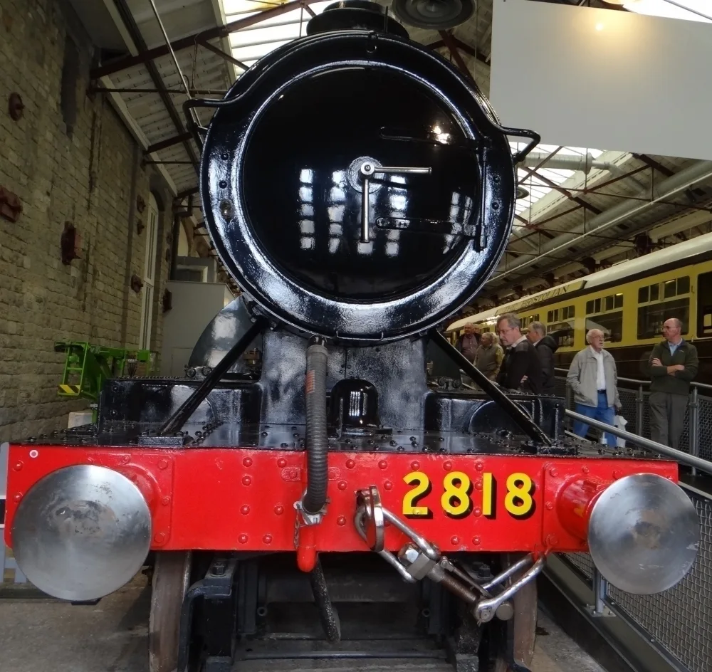 Front view of an old steam railway engine in a museum.