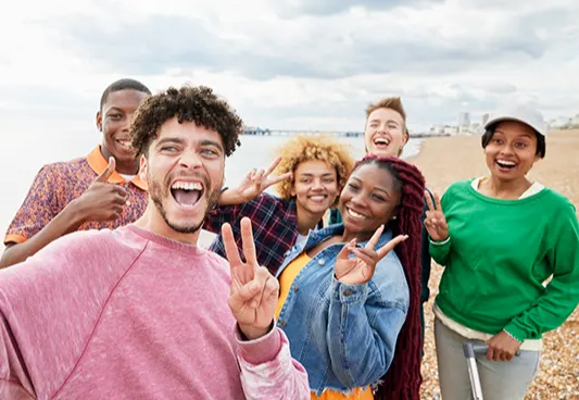 A multi-ethnic group of young people enjoying a day out on the beach and taking a selfie