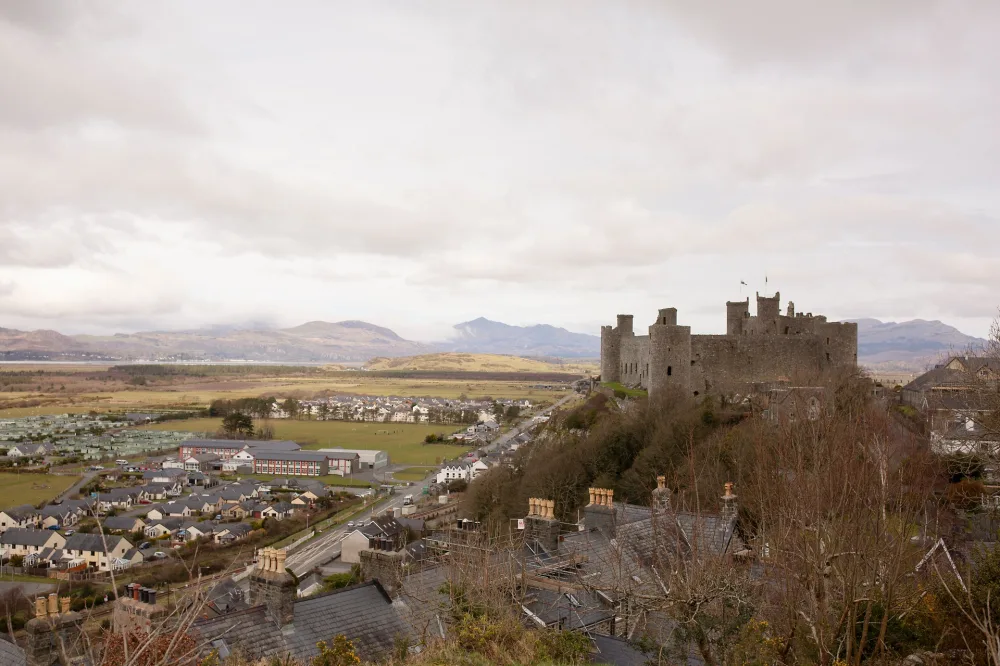 An ancient stone castle on a hill looking across green fields dotted with buildings. 