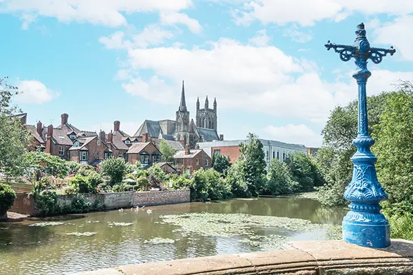 A view across a river to a village with a church, on a sunny day. 